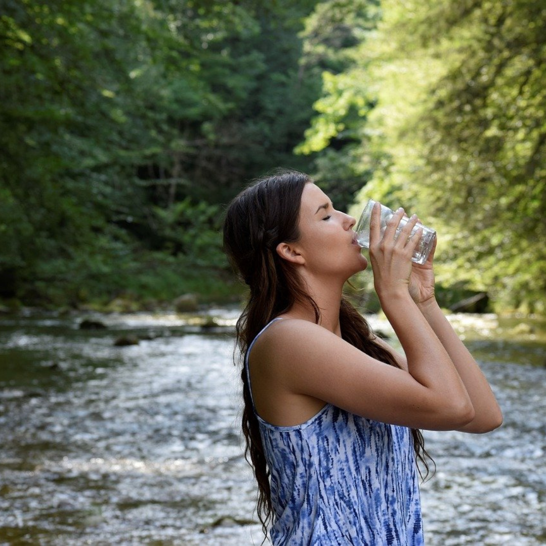 girl drinking water in front of river photo 